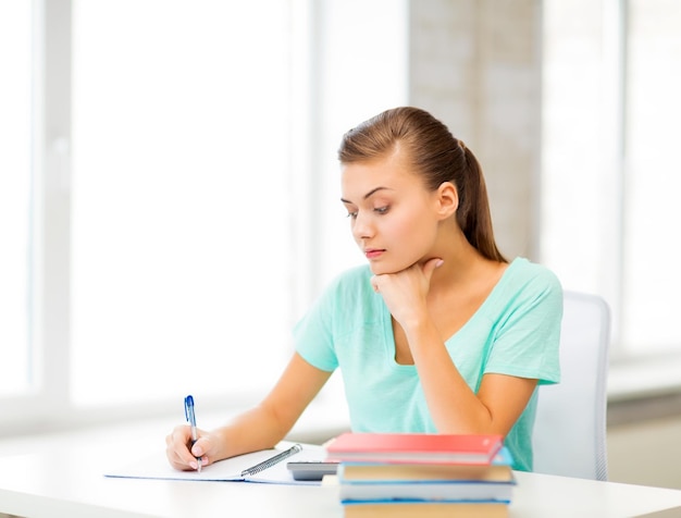 foto di uno studente stanco che scrive sul taccuino