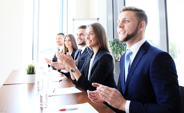 Foto di uomini d'affari felici che applaudono alla conferenza, si concentrano sulla ragazza sorridente