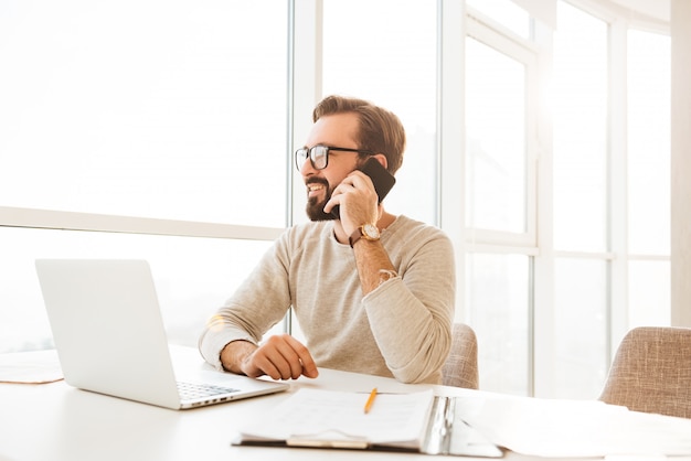 Foto di uomo d'affari in abbigliamento casual godendo parlando sul telefono cellulare, mentre si lavora a casa