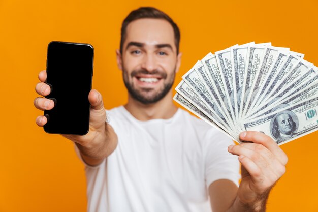 Foto di uomo europeo anni '30 in abbigliamento casual tenendo il cellulare e fan di soldi, isolato