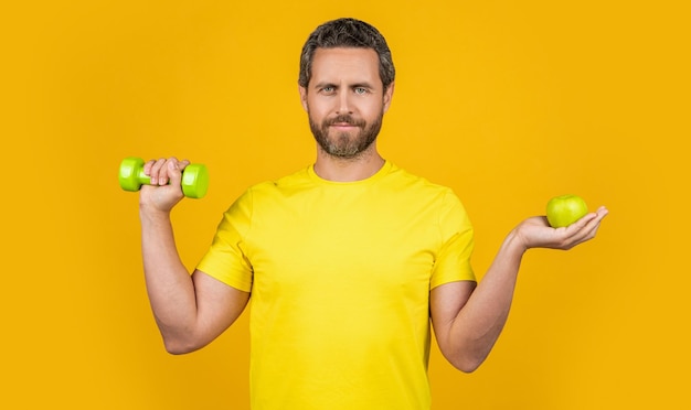 Foto di uomo fitness positivo con frutta mela sana e uomo fitness bilanciere con frutta sana