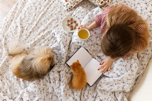 Foto di vista laterale dall'alto di una ragazza caucasica felice con i suoi animali domestici preferiti Kitten e il cane pechinese