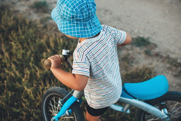 Foto di vista superiore di un ragazzo caucasico con cappello blu in sella a una bicicletta nel campo