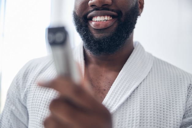 Foto focalizzata su una persona di sesso maschile che mostra il suo sorriso mentre trascorre la mattinata da solo a casa