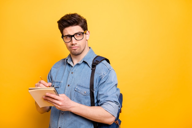 Foto girata dello studente creativo interessato che scrive le sue idee con la camicia del denim dei jeans della setola sul fronte vicino alla parete di colore vivido isolata spazio vuoto