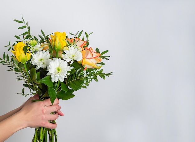 Foto gratuita di una mano femminile che tiene un bouquet di fiori