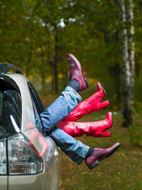 Foto i piedi dell'uomo e le ragazze fuori dall'auto su uno sfondo di natura