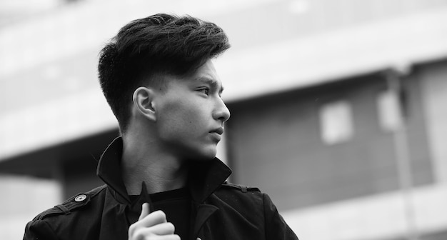 Foto in bianco e nero di un giovane asiatico all'aperto in posa alla telecamera