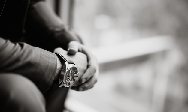 Foto in bianco e nero di un uomo d'affari in un vestito con un orologio in mano Sfondo sfocato Primo piano