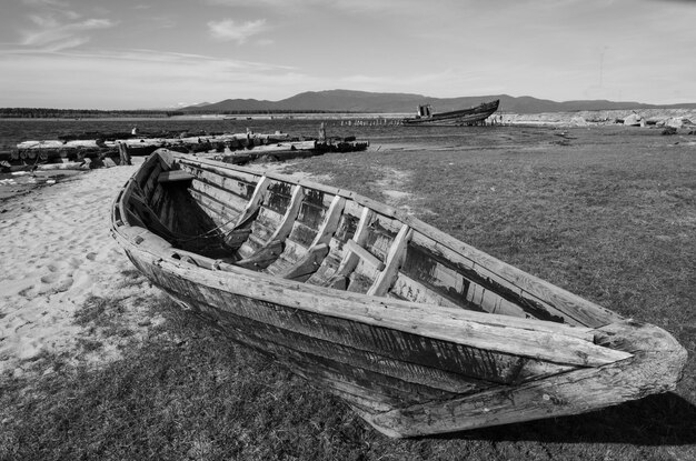 Foto in bianco e nero di una barca di legno sulla riva del fiume