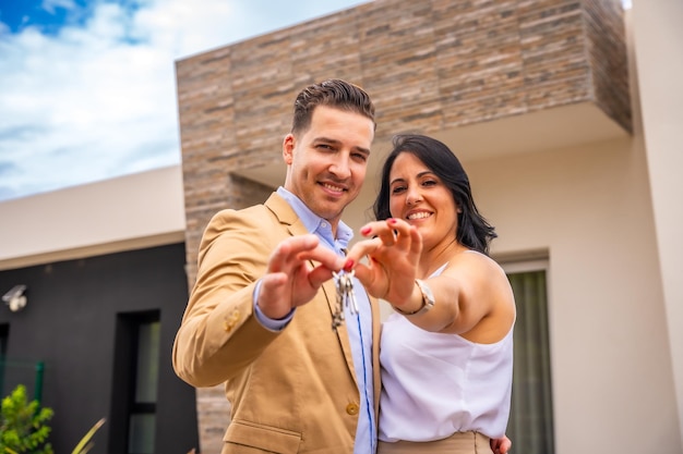 Foto in primo piano di una coppia sorridente che compra una nuova casa mostrando le chiavi