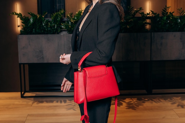 Foto in primo piano di una ragazza senza volto con una borsa rossa elegante nelle mani