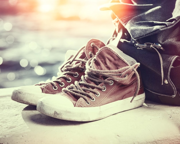 Foto in stile retrò di scarpe da ginnastica e zaino su vista sul mare