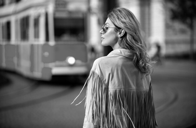 Foto in stile stradale di una donna elegante e alla moda che indossa abiti alla moda, modello che cammina per la strada di