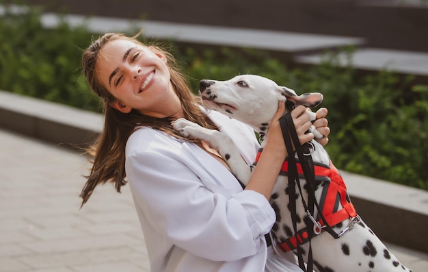 Foto in stile street di una donna elegante ed eccitata che cammina con il cane Cane che lecca e bacia una ragazza di lancio divertente