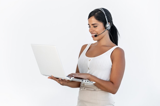 Foto in studio di una donna di telemarketing che sorride mentre lavora con un laptop su sfondo bianco