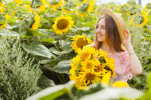 Foto incredibile, bellissima giovane donna bionda in piedi tra i girasoli