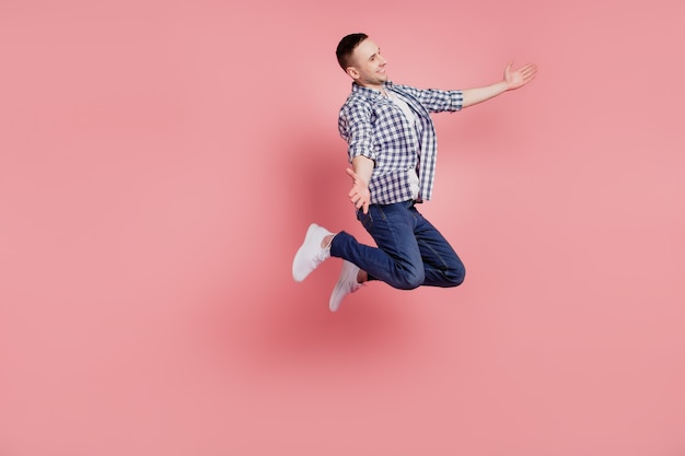 Foto laterale del profilo a tutta lunghezza di un giovane ragazzo felice sorriso positivo braccia aperte abbraccio salto isolato su sfondo di colore rosa