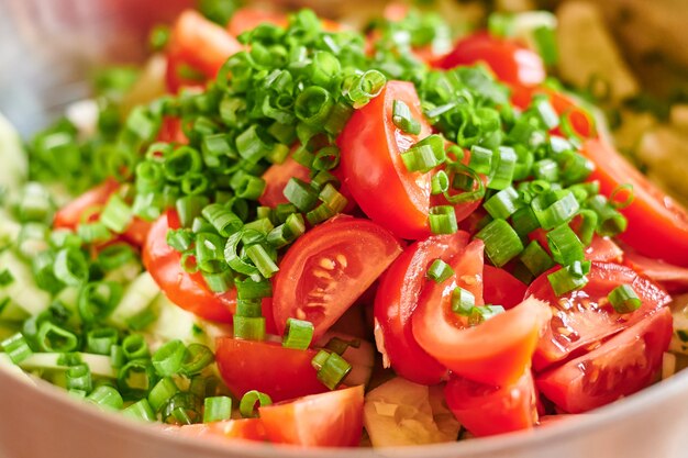 Foto macro di pomodori rossi freschi e insalata di cipolle verdi.