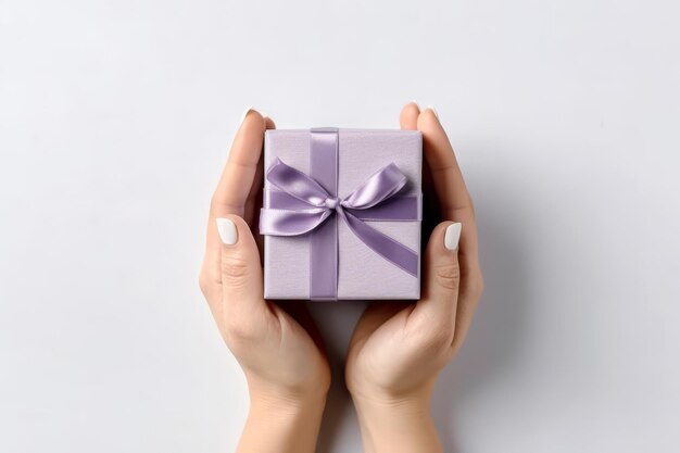 Foto mani femminili tengono una piccola scatola regalo su un tavolo bianco sfondo vista superiore