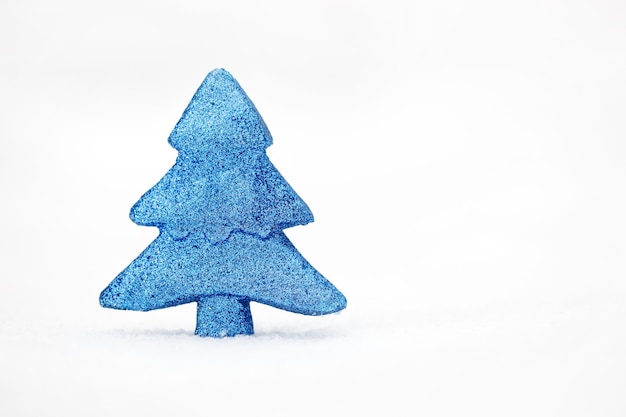Foto minimalista dell'albero giocattolo blu sulla neve reale al giorno d'inverno.