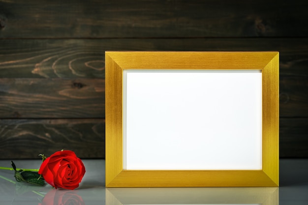 Foto mock up con cornice dorata e fiori di rose rosse sul tavolo con spazio di copia