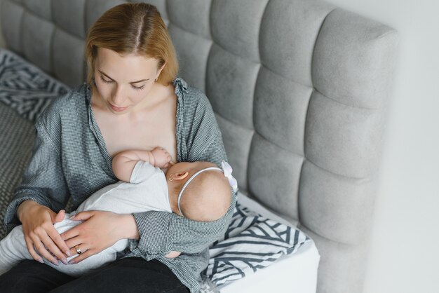 Foto morbida giovane madre che allatta al seno il suo bambino a casa