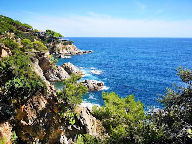Foto panoramica della costa rocciosa con il cielo con piante verdi alberi e case private La costa spagnola della Costa Brava il Mar Mediterraneo Turismo vivere in un posto bellissimo