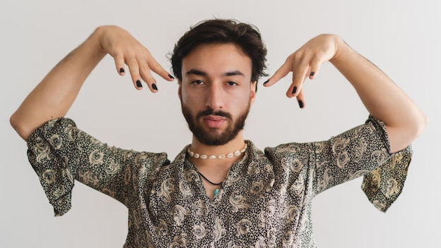 Foto panoramica di un giovane uomo latino gay queer che guarda la fotocamera mentre posa su uno sfondo bianco Foto artistica