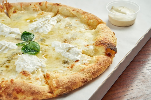 Foto per la consegna della pizza. Pizza ai 4 formaggi con gorgonzola, mozzarella, parmigiano e straccella in una scatola di cartone