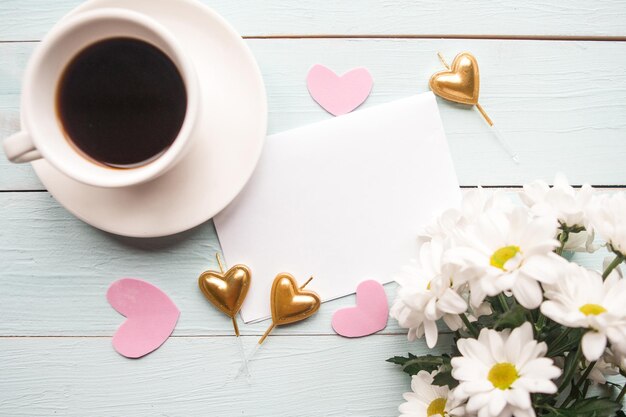 Foto piatta con bouquet di fiori tazza di caffè e bianco modello vuoto su sfondo di legno bellissimo giorno delle madri o biglietto di auguri di matrimonio