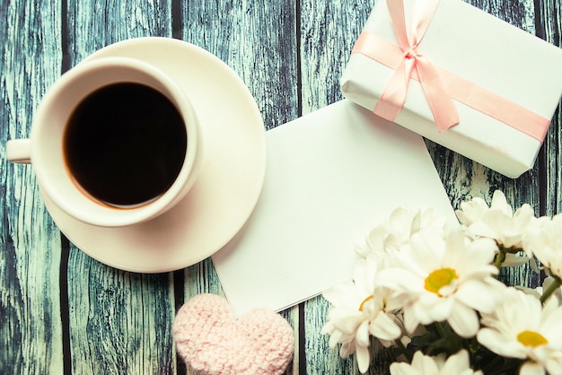 Foto piatta con scatola regalo di tazza di caffè e bouquet di fiori su sfondo di legno Copia spazio per il testo biglietto di auguri di compleanno o di Giornata delle Madri