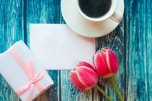 Foto piatta con scatola regalo per tazze di caffè e tulipani rossi su sfondo di legno Bellissimo giorno della madre Giorno della donna o Valentino biglietto di auguri Modello di biglietto da auguro per il giorno della madre