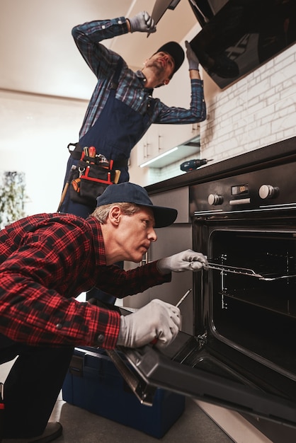 Foto produttiva insieme di due meccanici che lavorano in cucina