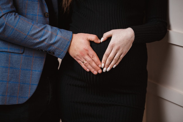 Foto ragazza incinta, gravidanza, primo piano, vestito nero, mani sulla pancia