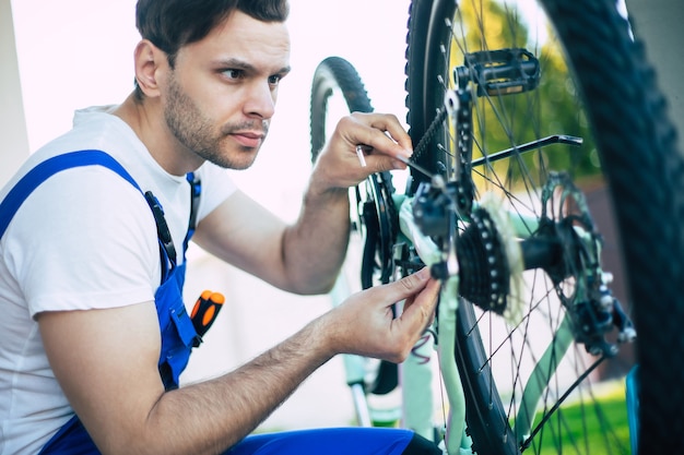 Foto ravvicinata del riparatore di biciclette con lo strumento in mano durante il fissaggio della bicicletta