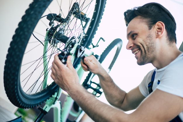 Foto ravvicinata del riparatore di biciclette con lo strumento in mano durante il fissaggio della bicicletta