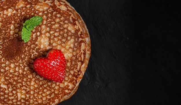 Foto ravvicinata della pila di frittelle con fragola a forma di cuore