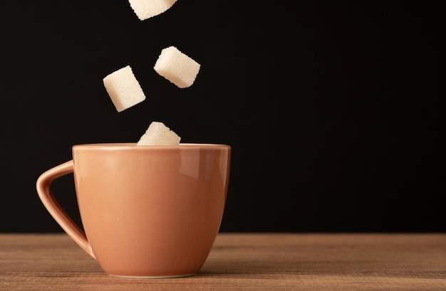 Foto ravvicinata della tazza di caffè e degli zuccheri a cubetti galleggianti