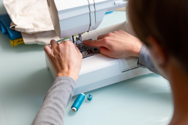 Foto ravvicinata delle mani femminili di Tailor che preparano la macchina da cucire