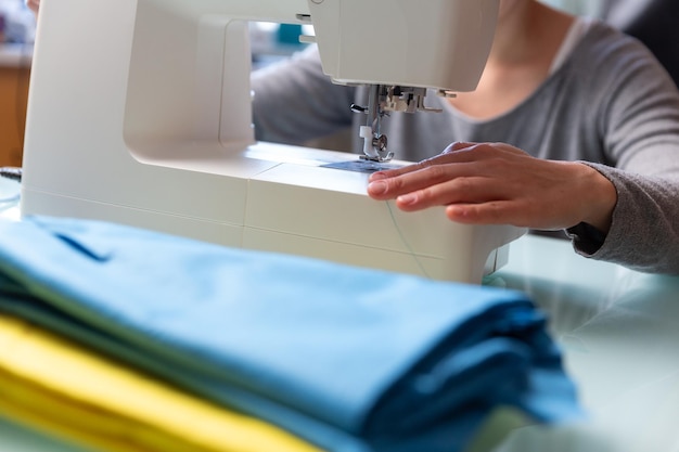 Foto ravvicinata delle mani femminili di Tailor che preparano la macchina da cucire