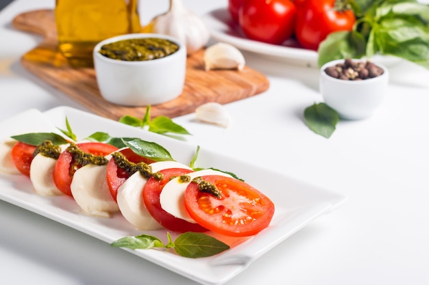 Foto ravvicinata di insalata caprese con pomodori maturi, basilico, mozzarella di bufala.