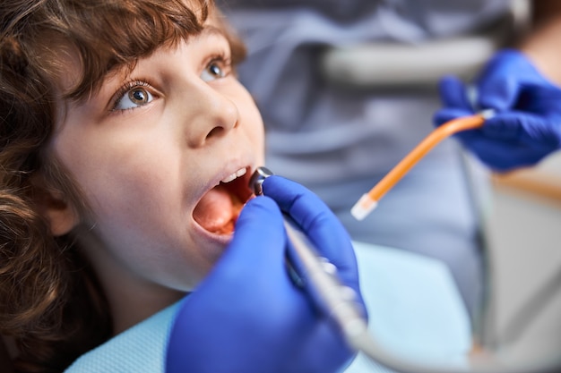 Foto ravvicinata di un bambino che apre ampiamente la bocca mentre il dentista usa il trapano dentale per cure mediche medical