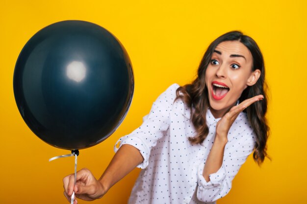 Foto ravvicinata di una bella donna felice eccitata con un palloncino di elio nero in mano come un simbolo del venerdì nero e della giornata dello shopping