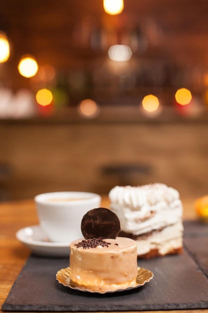 Foto ravvicinata di una deliziosa torta al cioccolato con un gustoso biscotto in cima. Mini torte gustose in una caffetteria. Dolci della tradizione.