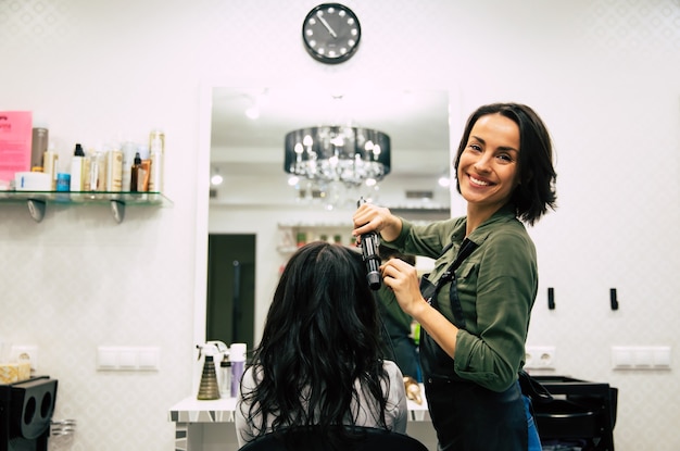 Foto ravvicinata di una splendida donna con bei capelli mossi, che si fa fare i capelli in un salone di bellezza.