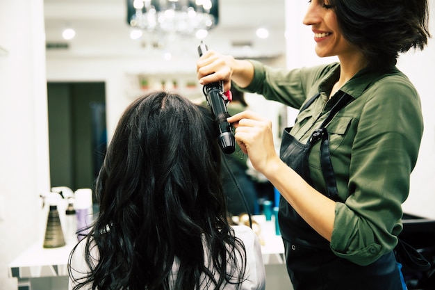 Foto ravvicinata di una splendida donna con bei capelli mossi, che si fa fare i capelli in un salone di bellezza.