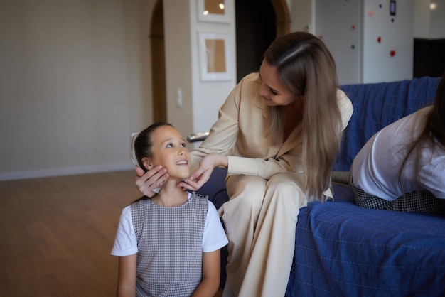 Foto ravvicinata di una studentessa sorridente felice con lunghi capelli scuri ricci e la sua bella mamma che si sta spazzolando i capelli