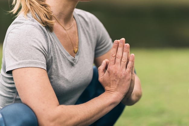 Foto ritagliata con vista ravvicinata delle mani di una donna palmo a palmo mentre fa yoga in un parco.