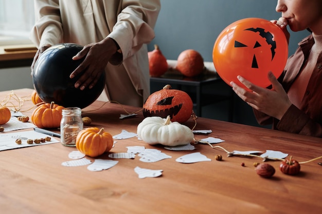 Foto ritagliata di due giovani donne che soffiano i palloncini di Halloween